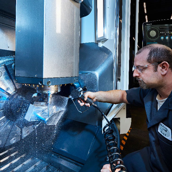 A technician sprays water on the 5-axis machine in LLNL Engineering’s Main Bay