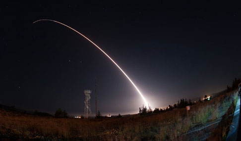 An intercontinental ballistic missile leaves a trail of light against a dark sky.