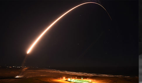An unarmed Minuteman III missile streaks across a dark sky.